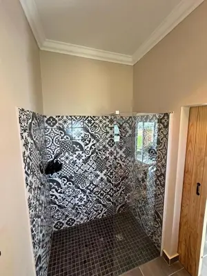a shower with a black and white patterned wall at La Vita Farm Stay in Wellington