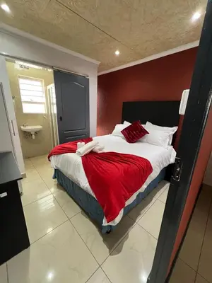 a bedroom with a large bed with a red wall at Our Home Guest House in Bellville