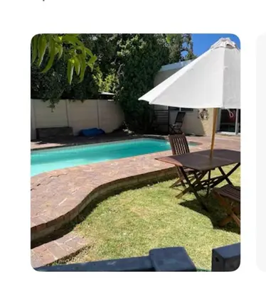 a table and an umbrella next to a swimming pool at Home from Home in Welton