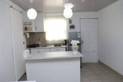 a kitchen with white cabinets and a vase of flowers on a counter at Optimum Stay Self Catering Accommodation - Twin Room 2 Single Beds in Parow