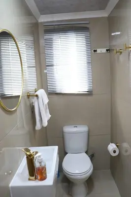 a bathroom with a toilet and a sink and a mirror at Optimum Stay Self Catering Accommodation - Twin Room 2 Single Beds in Parow