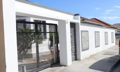 a white building with a gate in front of it at Optimum Stay Self Catering Accommodation - Twin Room 2 Single Beds in Parow