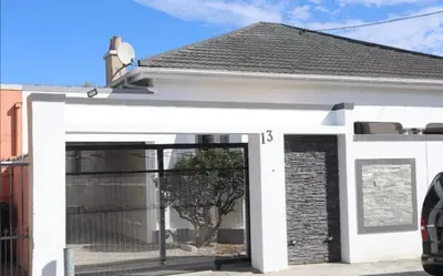 a white building with a large door with a tree inside at Optimum Stay Self Catering Accommodation - Twin Room 2 Single Beds in Parow