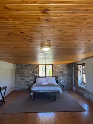 a bedroom with a bed in a stone wall at Avondrood Mountain House in Rawsonville