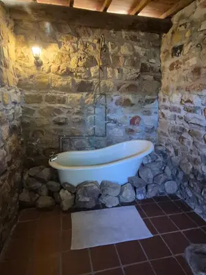 a stone bathroom with a tub in a stone wall at Avondrood Mountain House in Rawsonville