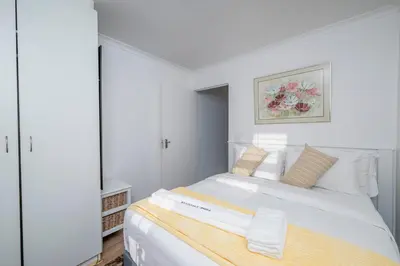 a white bedroom with a large white bed with a mirror at Prime Apartments in Richwood