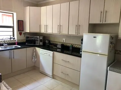 a kitchen with white cabinets and a white refrigerator at Charming Self-Catering Apartment in Tygerberg Hills