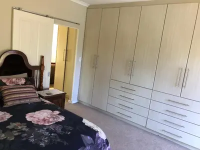 a bedroom with white cabinets and a bed at Charming Self-Catering Apartment in Tygerberg Hills
