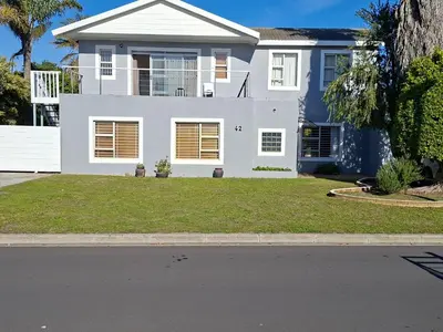 a white house with a green lawn in front of it at Leigh's home with dogs in Cape Town