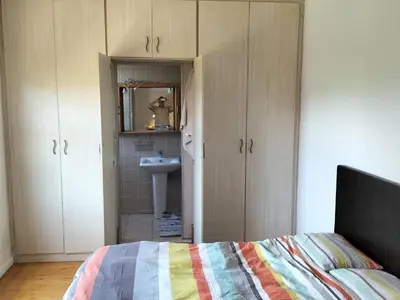 a bedroom with a bed and a sink and cabinets at Leigh's home with dogs in Cape Town