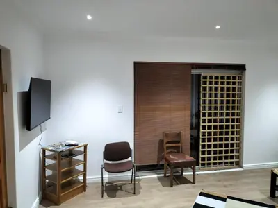 a living room with two chairs and a television at Leigh's home with dogs in Cape Town