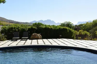 two chairs sitting on a patio next to a swimming pool at The Jordan Suites in Stellenbosch