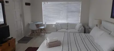 a white bedroom with a white bed and a couch at Amanda's Place in Hermanus
