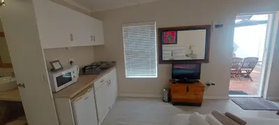 a kitchen with white cabinets and a tv in it at Amanda's Place in Hermanus