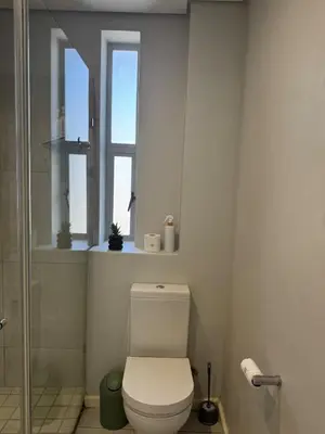 a bathroom with a toilet and two windows at Black & White Self Catering in Paarl