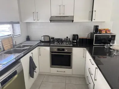 a kitchen with white cabinets and a stove top oven at Black & White Self Catering in Paarl