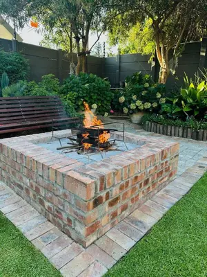 a brick fire pit in a yard with a bench at Lelani Self Catering Cape Town in Oakdale