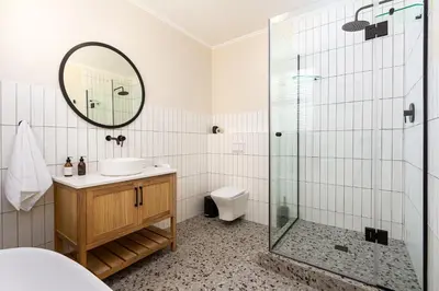 a bathroom with a shower and a sink and a mirror at Canal Front Apartment Cape Town in Cape Town