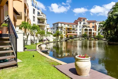 a river in a city with buildings and a bridge at Canal Front Apartment Cape Town in Cape Town