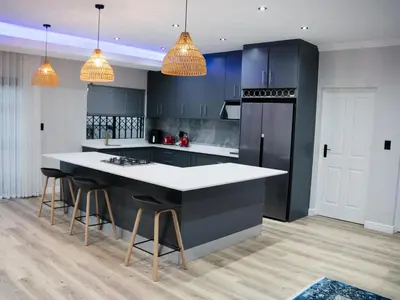 a kitchen with black cabinets and a white counter top at Bokwe's Guest House- Cape Town in Gordonʼs Bay