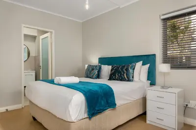 a bedroom with a large bed with a blue headboard at Mayfair 134 in Cape Town