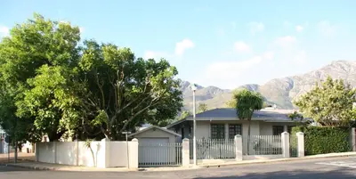 a house with a fence and mountains in the background at Cape Robin Cottage in Franschhoek