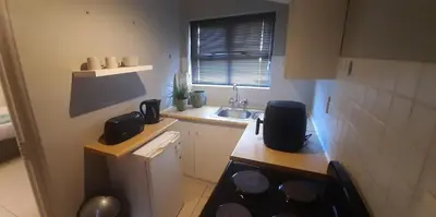 a small kitchen with a sink and a stove at Apartment in Flamingo Vlei in Cape Town