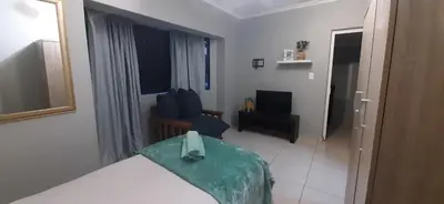 a bedroom with a bed and a chair in a room at Apartment in Flamingo Vlei in Cape Town
