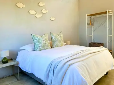 a bedroom with a bed with blue sheets and pillows at Silvertree Collective Ocean and Mountain View in Bettyʼs Bay