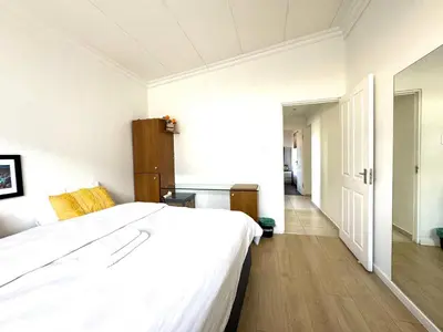 a bedroom with a large white bed and a hallway at Cheap Affordable Self-Catering Double Room with Pool, WiFi and Braai in Cape Town