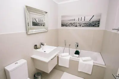 a white bathroom with a sink and a toilet at Apartments on Century in Cape Town