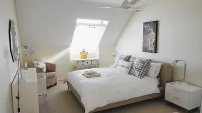 a bedroom with a bed and a chair and a window at Dolphin Beach Penthouse in Cape Town