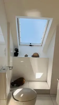 a bathroom with a white toilet and a window at Dolphin Beach Penthouse in Cape Town
