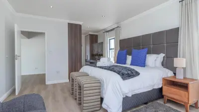 a large bedroom with a large bed with blue pillows at Ocean Whisper Villa near Westcliff coastal paths in Hermanus