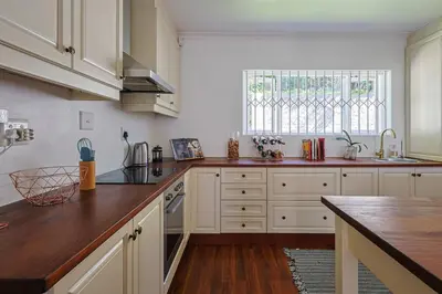 a kitchen with white cabinets and a wooden counter top at Fully Equipped Claremont Home with Pool & Style in Cape Town