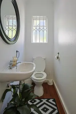 a bathroom with a toilet and a sink and a mirror at Fully Equipped Claremont Home with Pool & Style in Cape Town