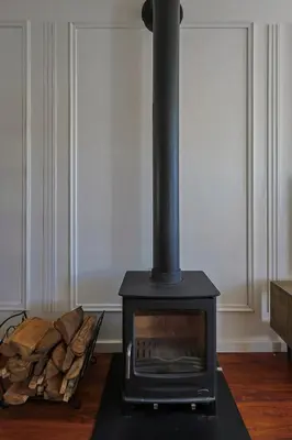 a black stove in a room with a pile of wood at Fully Equipped Claremont Home with Pool & Style in Cape Town