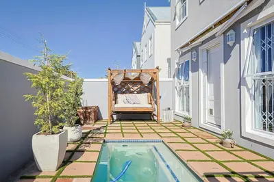 a small backyard with a bed and a swimming pool at Fully Equipped Claremont Home with Pool & Style in Cape Town
