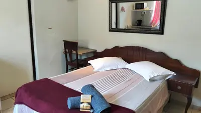 a bedroom with a bed with a mirror on the wall at Overnight Lodge in Cape Town