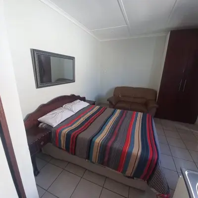 a bedroom with a bed and a television on the wall at Overnight Lodge in Cape Town