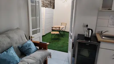 a living room with a couch and a table and a kitchen at Kenwyn Micro Cottage in Cape Town