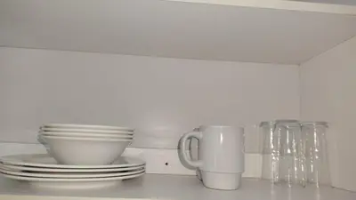 a white kitchen counter with plates and cups on it at Kenwyn Micro Cottage in Cape Town
