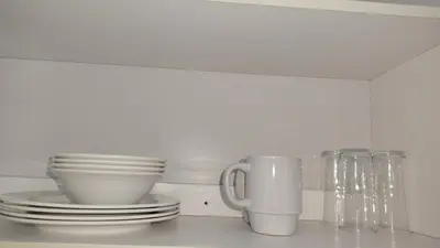 a white kitchen counter with plates and cups at Kenwyn Micro Cottage in Cape Town