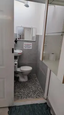 a bathroom with two toilets and a sink and a shower at Kenwyn Micro Cottage in Cape Town