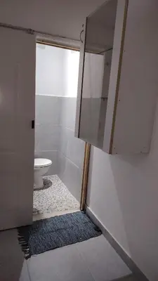 a bathroom with a toilet and a cabinet and a rug at Kenwyn Micro Cottage in Cape Town
