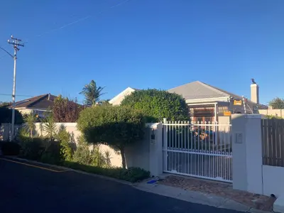 a white fence in front of a house at Cozy garden Guest Suite in charming Claremont in Cape Town