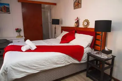 a bedroom with a large bed with red and white pillows at Fully Furnished Room and en-suite in Cape Town