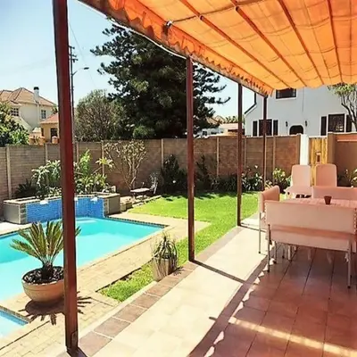 a patio with a pool and an orange umbrella at Fully Furnished Room and en-suite in Cape Town