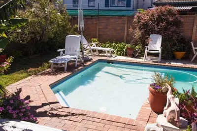 a swimming pool with two lawn chairs and two chairs at Fully Furnished Room and en-suite in Cape Town