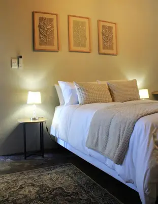 a bedroom with a bed and a table with a lamp at Lategansrus at Helpmekaar Farm in Wellington